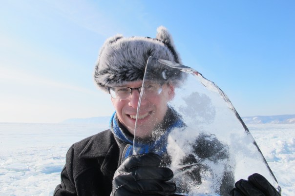UNI Geography Professor Andrey Petrov, in furry hat and gloves, holds a piece of Lake Baikal ice in front of his face  during his most recent Siberian visit.