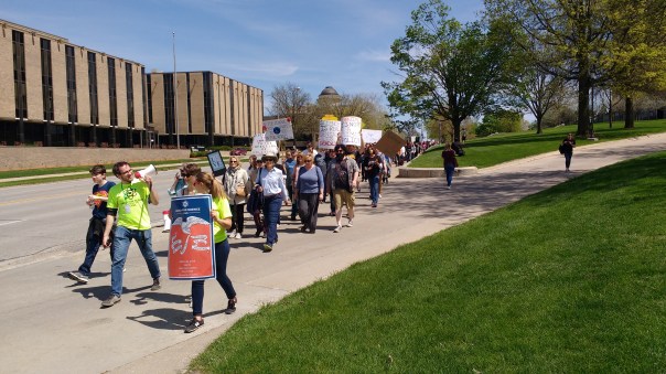 The leading edge of the March for Science Iowa coming down Grand Avenue, with organizer Shamus Roeder wielding the bullhorn.