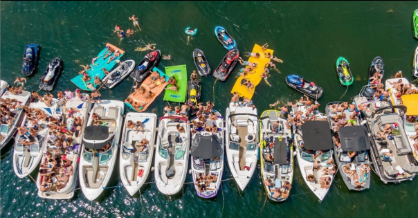 Boats tied together in a row with swimmers and floating air mattresses at one of the Iowa Great Lakes.